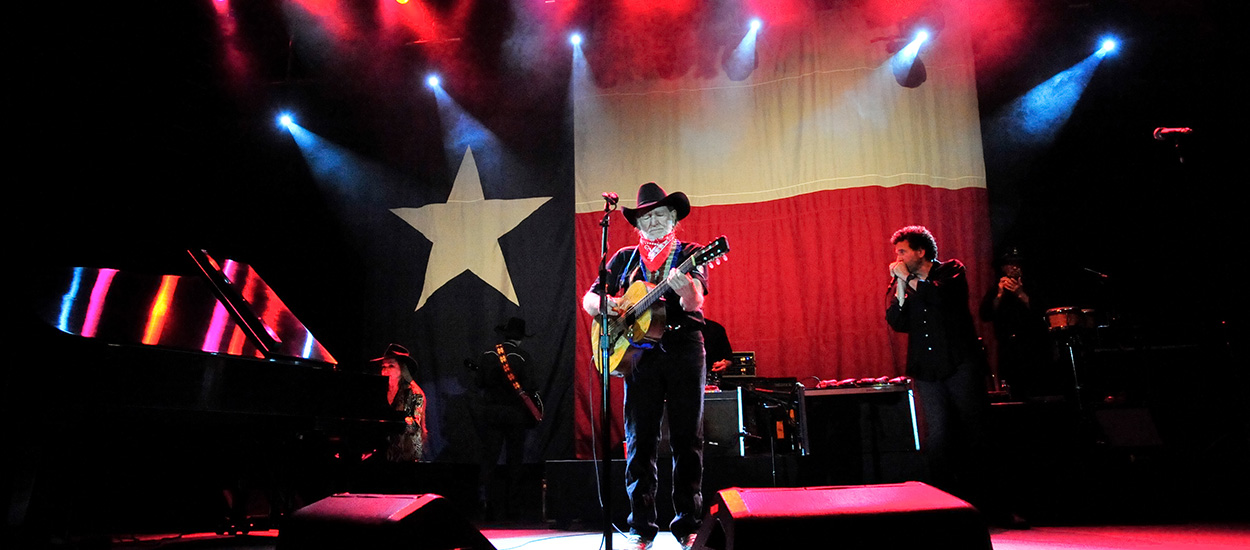 Willie Nelson playing guitar on stage